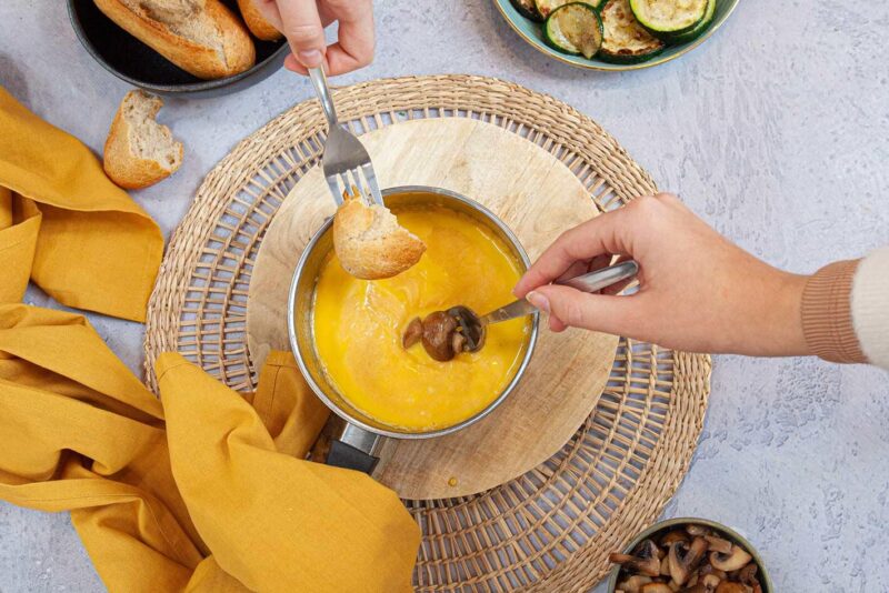 Fondue au fromage avec de la baguette et des légumes grillés